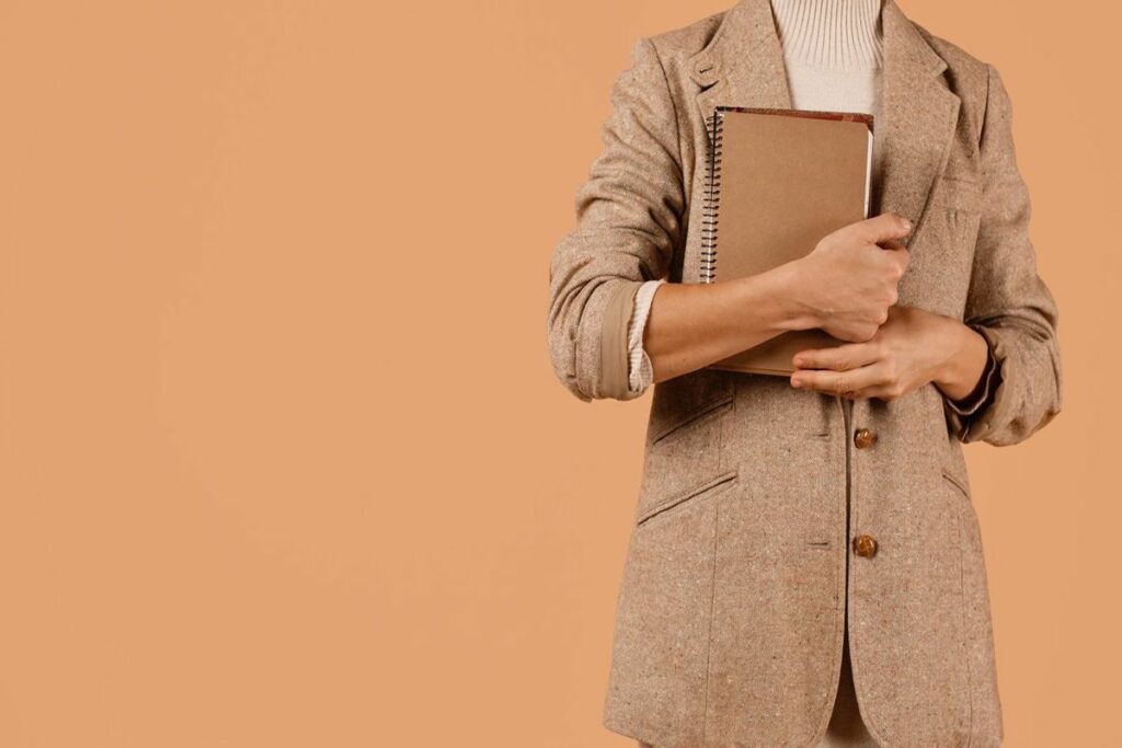 Profesional con blazer sosteniendo una libreta, representando organización, planificación y trabajo por proyectos.